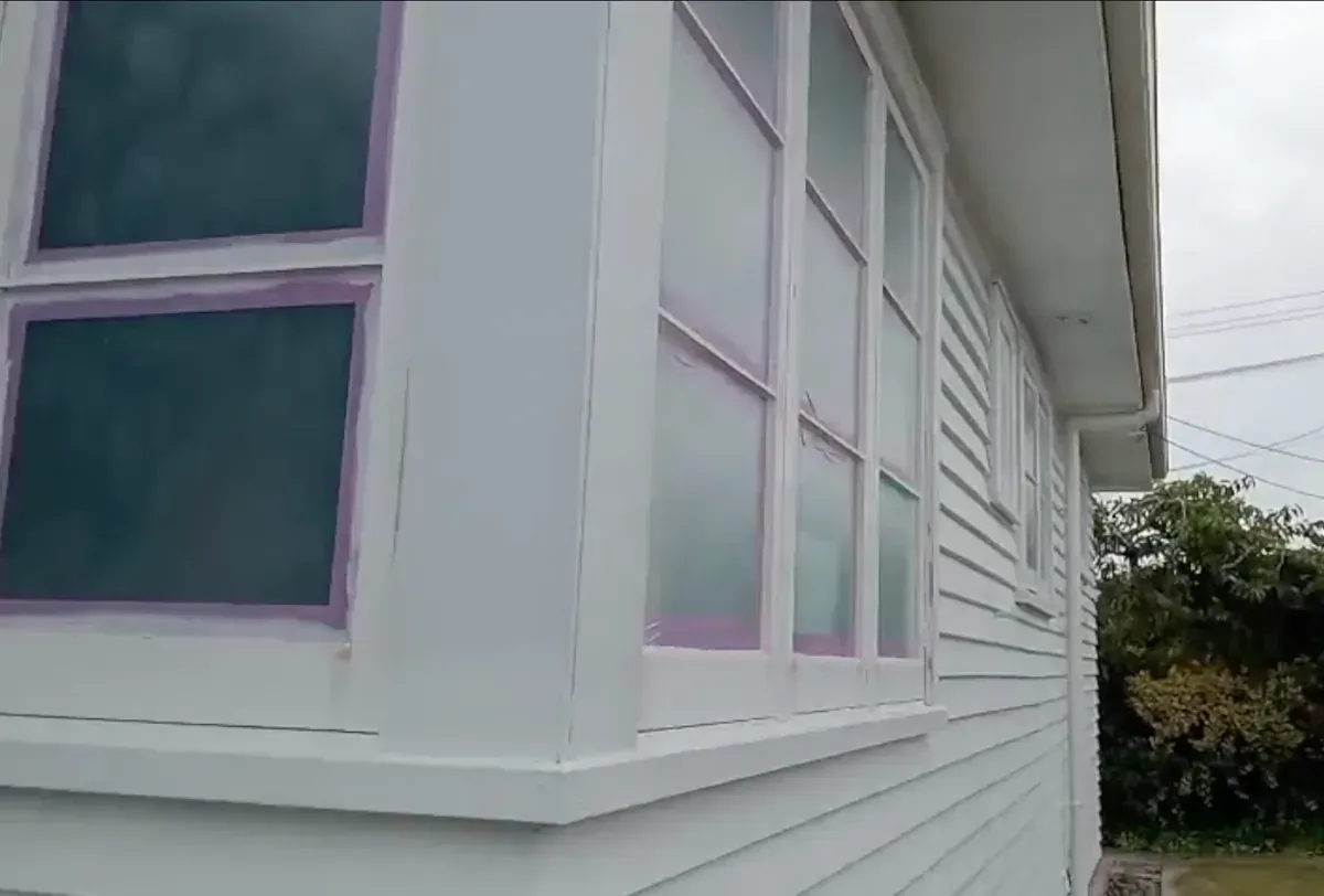 Liquid masking around the windows during preparation on the Hamilton weatherboard restoration project