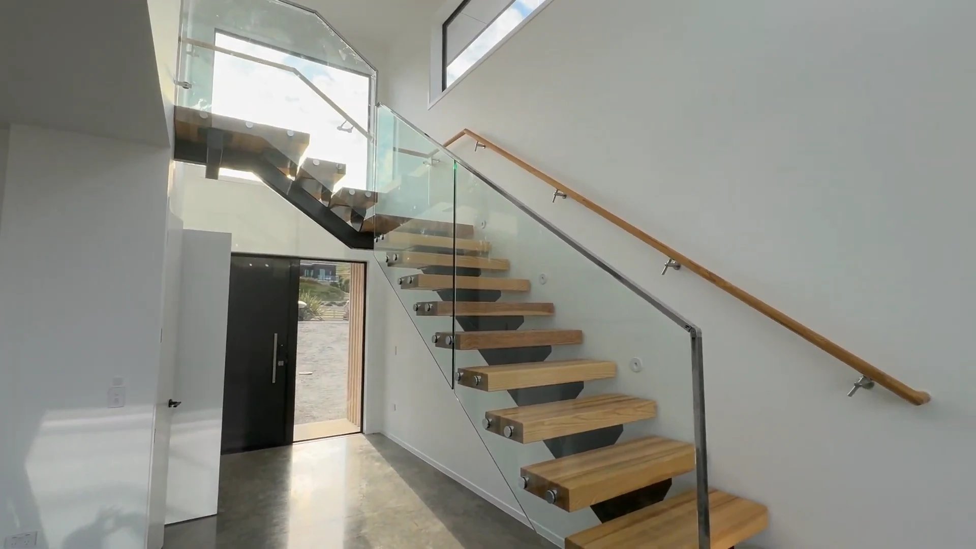 White painted walls around the timber and glass staircase at the Pirongia new-build project