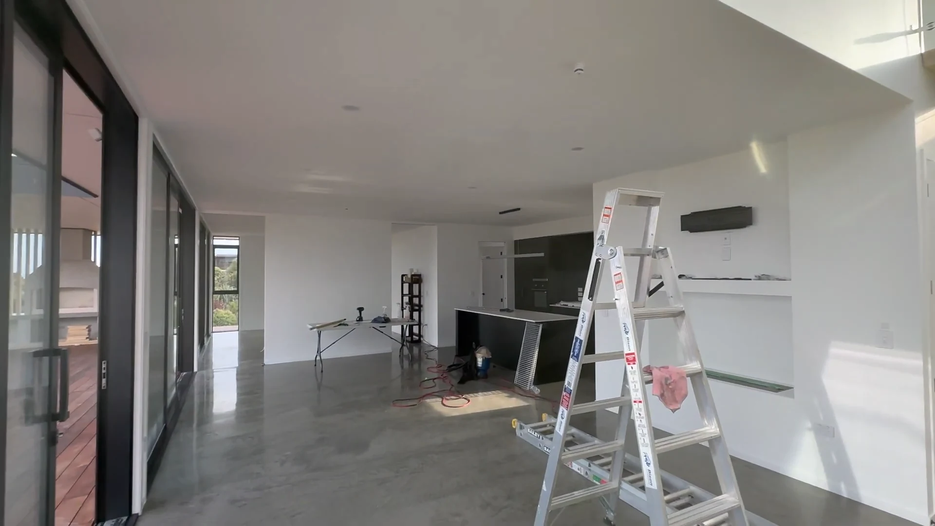 A ladder and work equipment in the painted living area while interior finishing continues at Pirongia
